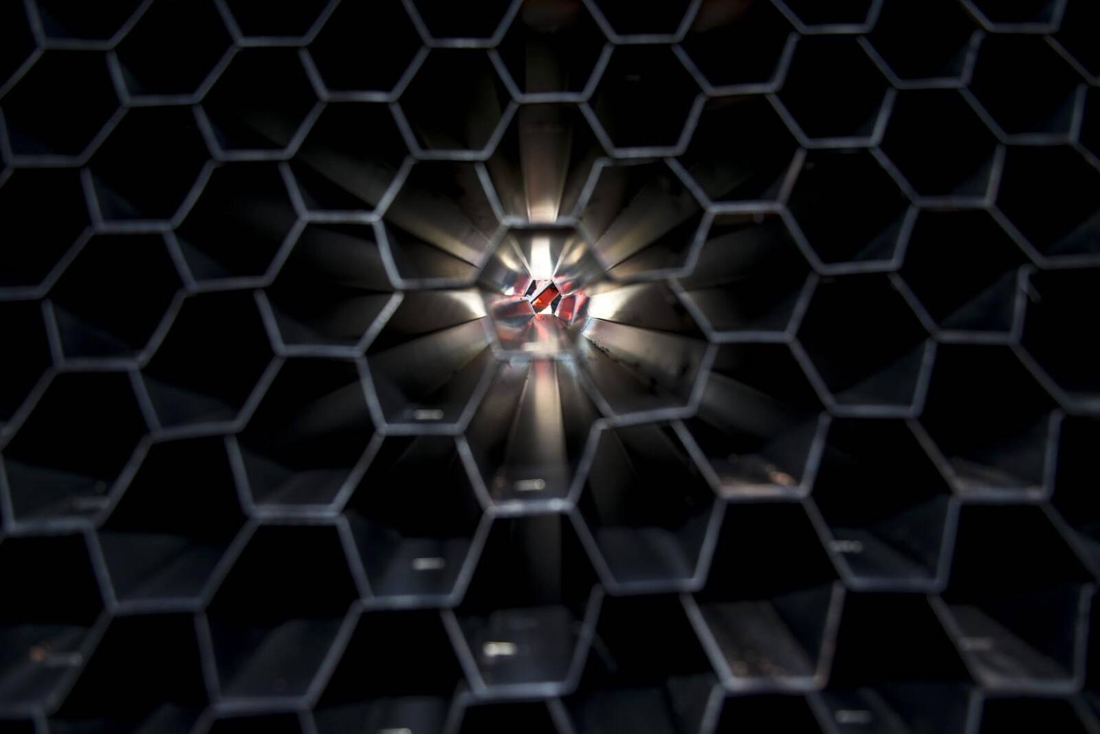 Abstract close-up of light rays glowing at the center of a honeycomb-patterned metal grille