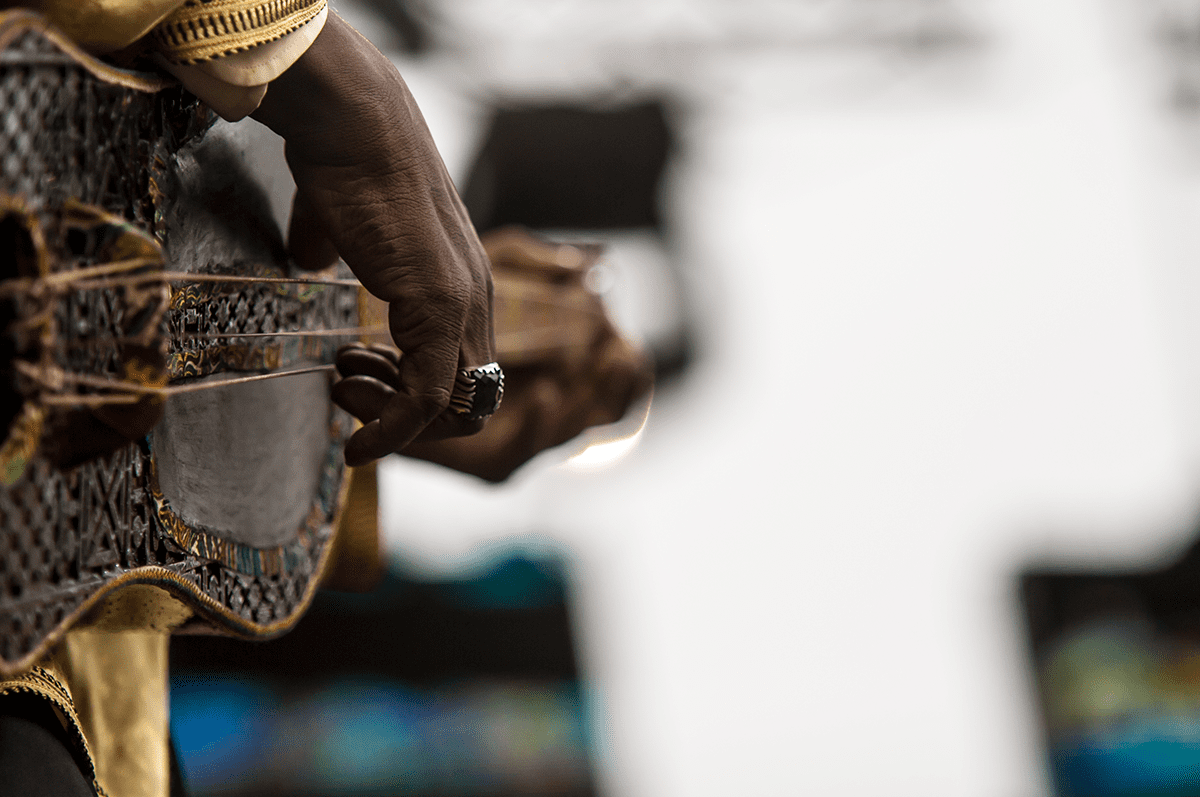 Close-up of a hand with a ring resting on an ornate gold and metal decorated instrument case