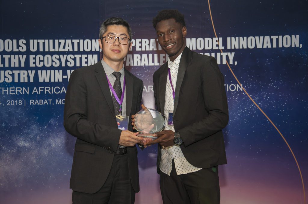 Two men in suits posing with a glass award trophy at a Huawei telecommunications industry event