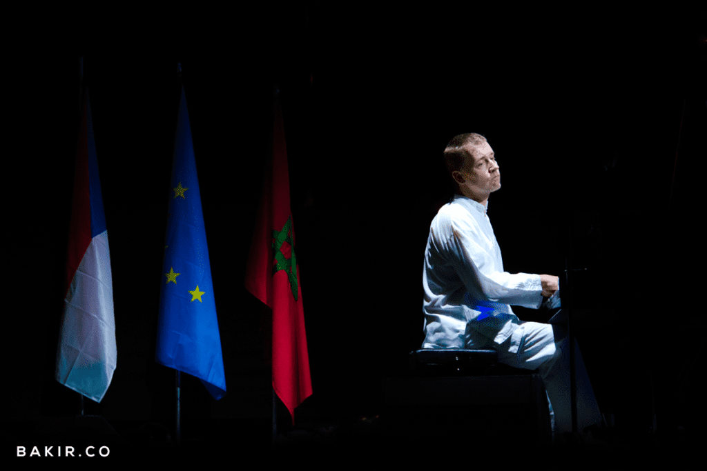 Musician seated on stage beside French, EU and Moroccan flags at the Jazz au Chellah festival in Rabat