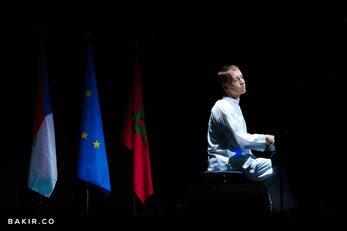 Musician seated on stage beside French, EU and Moroccan flags at the Jazz au Chellah festival in Rabat