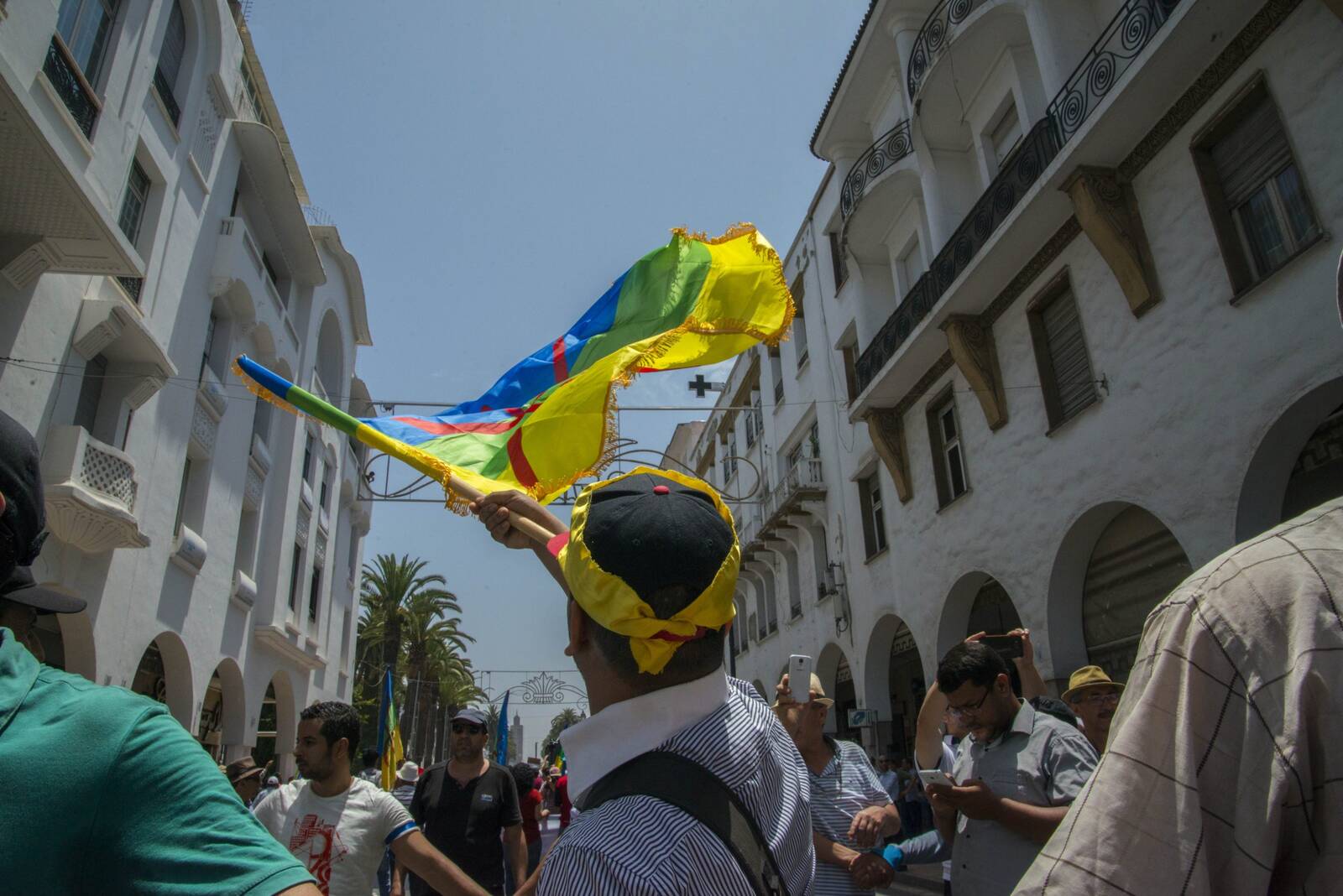 Crowd marching in the street waving colorful Amazigh flags during a solidarity demonstration