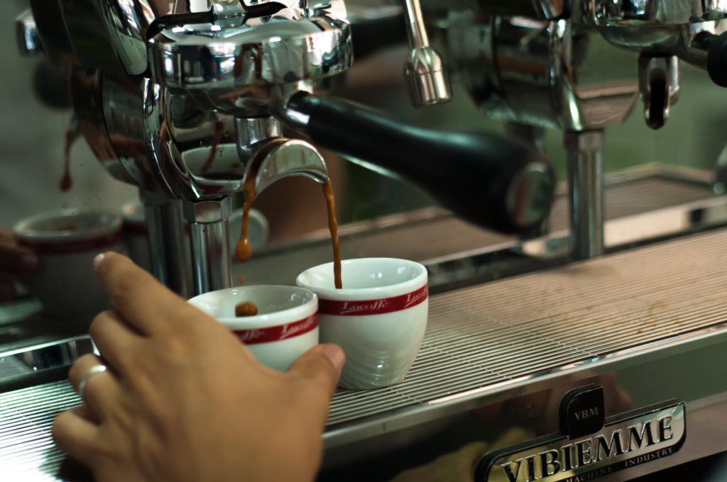 Espresso being poured into two white cups from a professional coffee machine, close-up shot