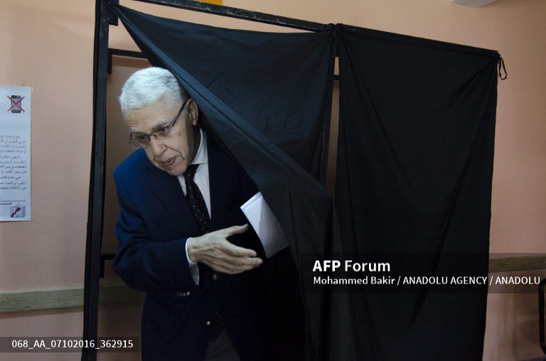 Man casting his vote behind a black voting booth curtain during Moroccan parliamentary elections