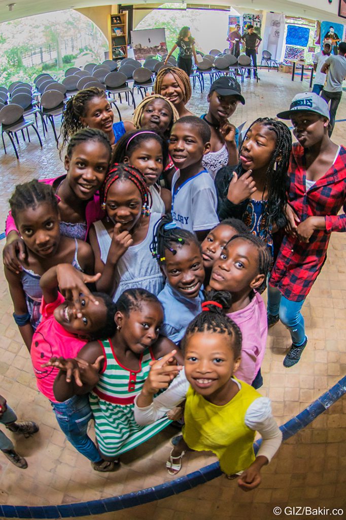 Large group of smiling children posing together indoors for a World Refugee Day event with GIZ Morocco