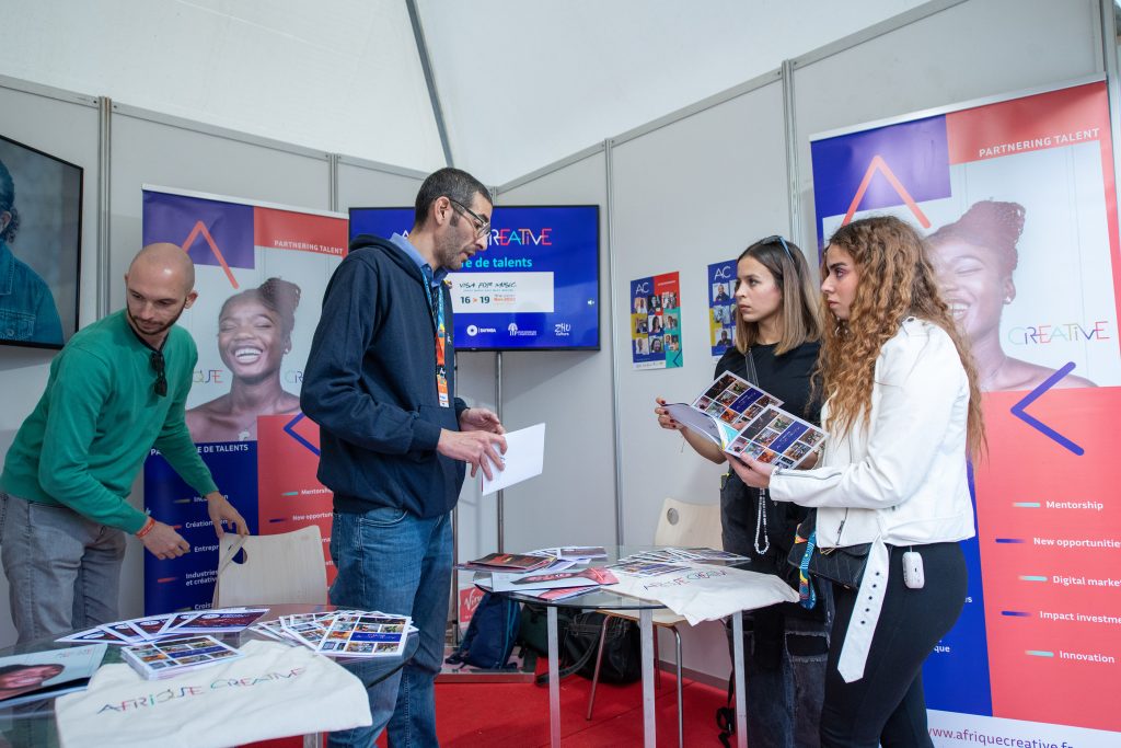 Attendees discussing materials at the Afrique Creative booth during the Visa For Music (V4M) forum