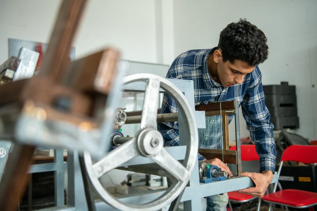 Trainee working with mechanical automation equipment at a vocational Competence Center workshop in Morocco