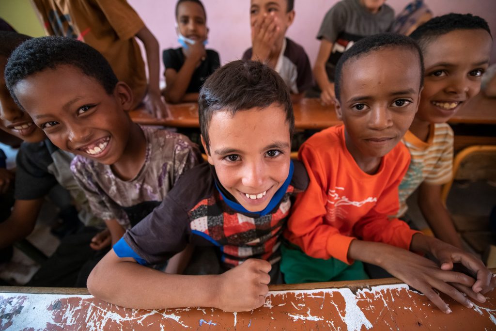 Group of smiling Moroccan schoolboys in a classroom, part of a school life photo series for IFEGH