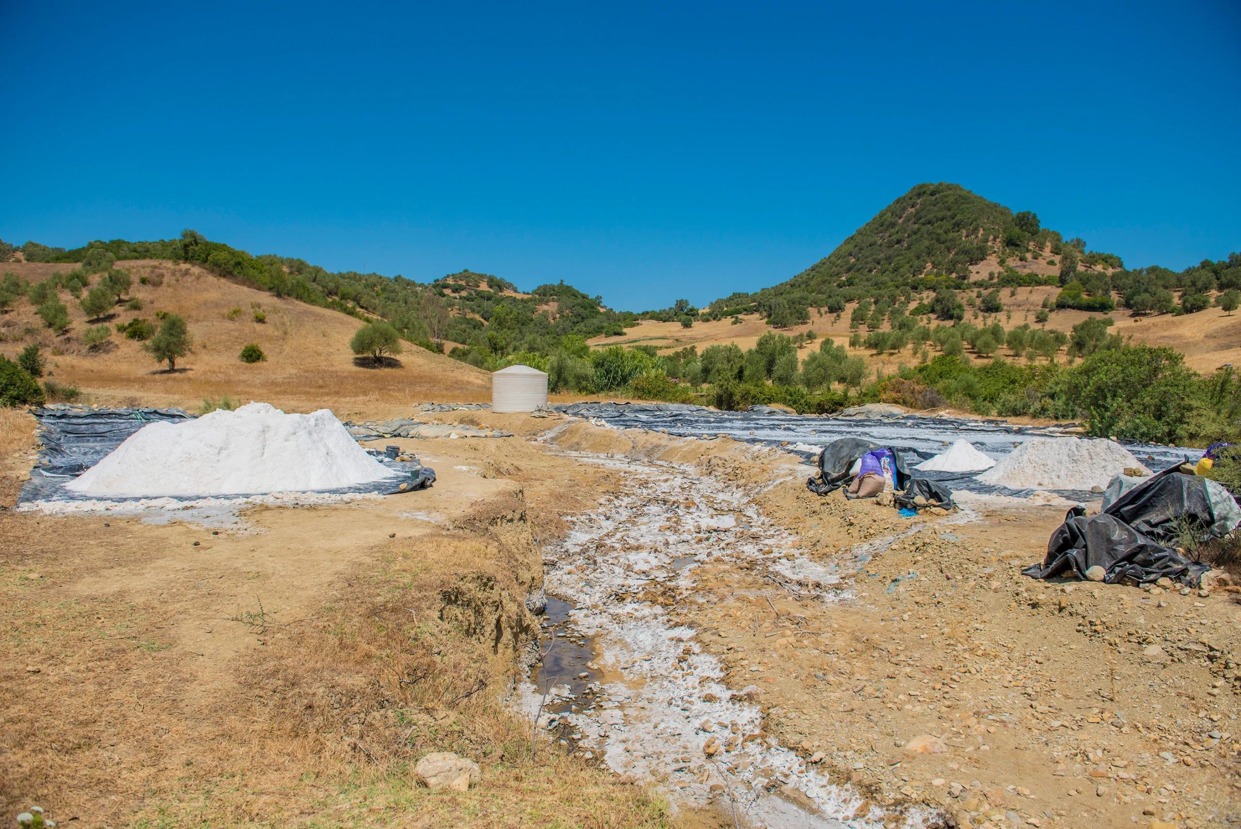 Aerial view of a traditional salt harvesting site on a hillside in rural Morocco under a clear blue sky